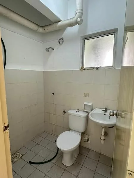 Bathroom features: white tiled walls, grey tiled flooring, one-piece toilet, single-sink vanity, chrome basin mixer faucet, shower head with wall mount, window for natural light, exposed plumbing, mirror above sink.