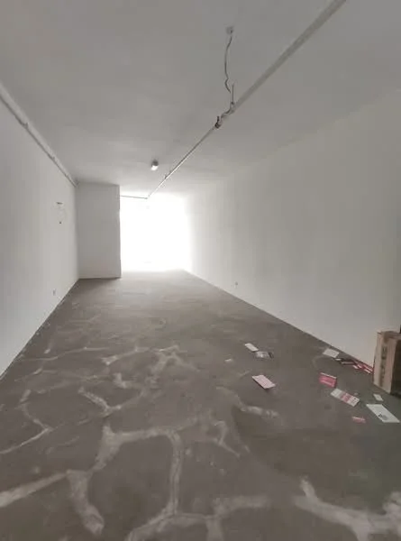 Room features: white painted walls, concrete flooring, exposed ceiling, natural light from entrance, no visible fixtures or furniture, clean and empty space, minimal decor, unfinished appearance; style: minimalist.