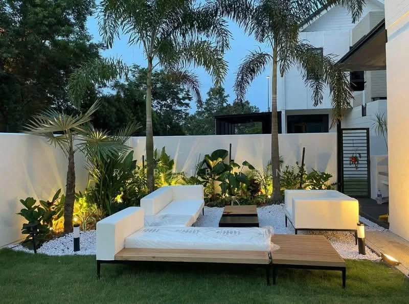 Exterior type: landscape garden; features: white painted walls, landscaped garden with tropical plants, palm trees, white outdoor sofas, wooden coffee table, decorative gravel, outdoor lighting, manicured lawn; style: modern.