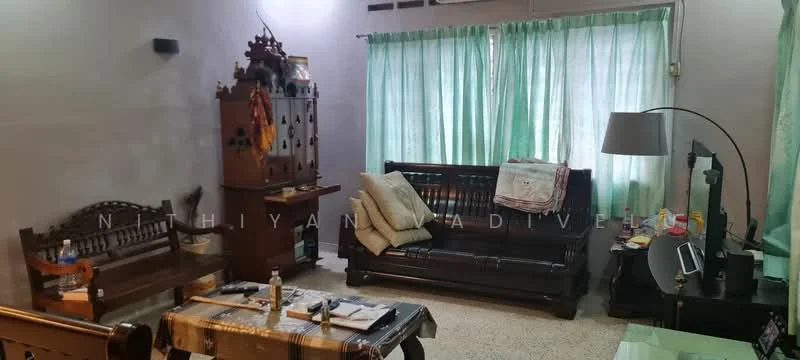 Living features: brown wooden sofa, cream cushions on sofa, wooden coffee table, decorative wooden cabinet, green sheer curtains, light grey painted walls, carpeted flooring, floor lamp, wall-mounted TV, wooden bench, decorative items on cabinet; style: traditional.