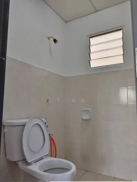 Bathroom features: white ceramic toilet, wall-mounted bidet spray, white tiled walls, light beige tiled flooring, small window with horizontal slats, exposed plumbing, wall-mounted toilet roll holder.