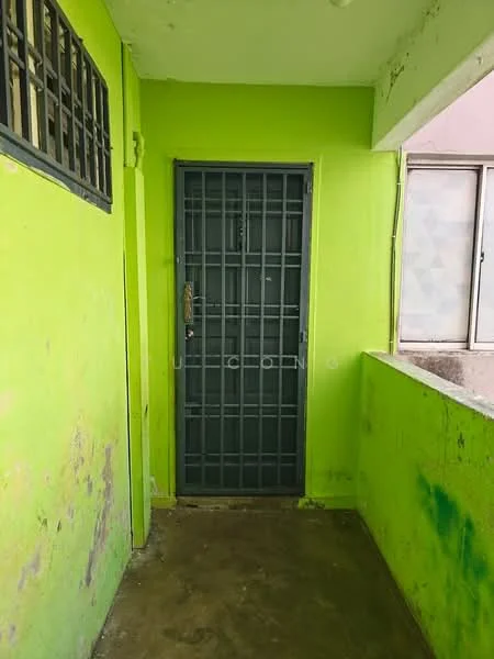 Room features: green painted walls, concrete flooring, metal security door, window with patterned glass, exposed concrete ceiling.