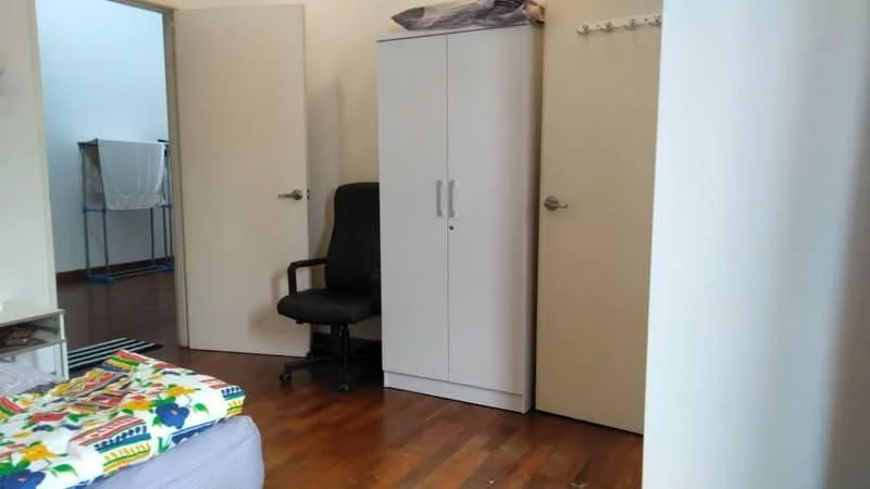 Room features: wooden flooring, white painted walls, built-in wardrobe, black office chair, door leading to another room, laundry area visible in background, striped area rug.