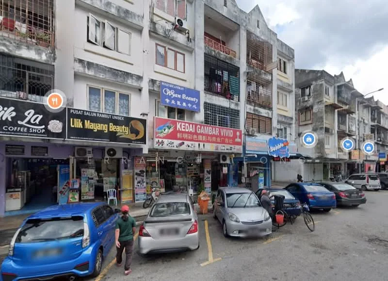 Exterior type: shophouse; features: multi-storey building, commercial units on ground floor, residential units above, balconies on upper floors, signage for various businesses, parking spaces in front, concrete facade, mixed-use development; style: modern.