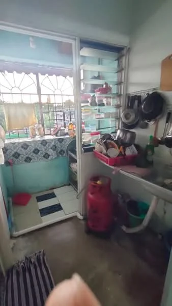 Kitchen features: green painted walls, tile backsplash with blue pattern, white cabinetry, stainless-steel sink, chrome faucet, gas cylinder, open shelving, ceramic tile flooring, window with metal grills, countertop with utensils and dishes, floor tiles in black and white pattern, kitchen appliances visible; view: garden.