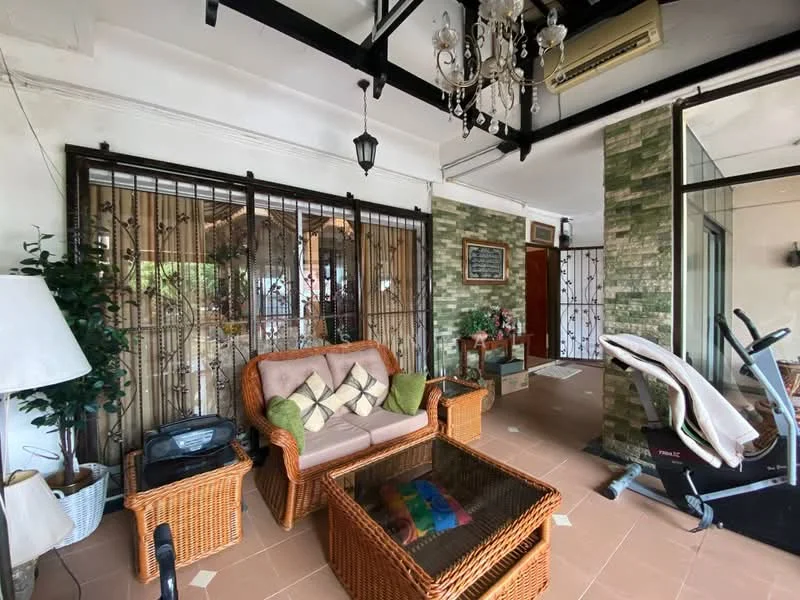Living features: rattan sofa with cushions, glass coffee table, decorative chandelier, exposed beams on ceiling, wall-mounted air conditioning unit, green stone feature wall, decorative wall panels, exercise bike, indoor plants, floor tiles with diamond pattern, lantern-style light fixture, metal security grille; style: contemporary.