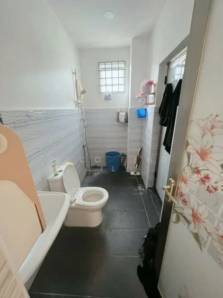 Bathroom features: white toilet, bathtub, grey tiled walls, black tile flooring, window with grid pattern, shelf with toiletries, towel rack, door with floral design.