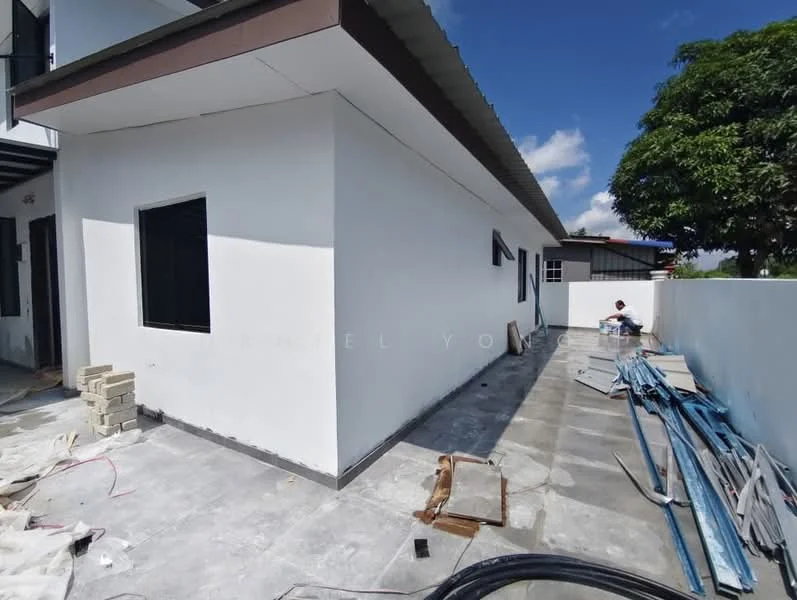 Exterior features: white painted facade, flat roof, concrete flooring, windows with black frames, surrounded by construction materials, manicured landscaping with trees, unfinished exterior wall, clear blue sky; style: modern.