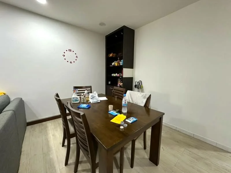 Dining features: wooden dining table, 4 wooden dining chairs, clock on wall, grey sofa in background, light-colored walls, laminate flooring, open shelving unit, decorative items on shelves; style: modern.