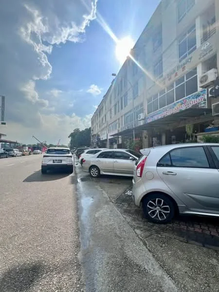 Exterior type: shophouse; features: multi-storey building, glass windows, signage above entrance, parking spaces in front, paved walkway, street view, surrounded by vehicles, urban setting; style: modern.