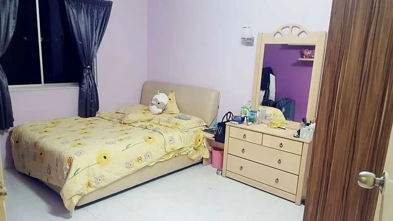Bedroom features: queen-size bed with beige upholstered headboard, yellow floral bedding, decorative pillow, light purple painted walls, white tiled flooring, large window with sheer curtains, wooden dresser with multiple drawers, mirror on dresser, small pink storage bin, table lamp on dresser; style: modern.