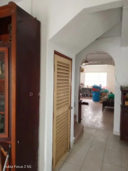Room features: white painted walls, tile flooring, wooden door with slatted design, arched doorway, ceiling with exposed beams, natural light from window, furniture visible in background, decorative cabinet.