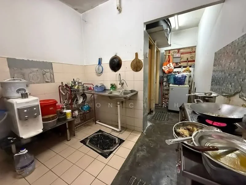 Kitchen features: single-bowl stainless-steel sink, chrome pull-down faucet, white tiled walls, cream tiled flooring, stainless-steel countertop, kitchen cabinets, water dispenser, stove with wok, refrigerator, open shelving, multiple cooking pots, cutting board, kitchen utensils.