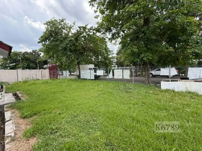 Exterior features: manicured lawn, mature trees, fenced perimeter, gravel pathway, parking area visible, surrounding greenery.