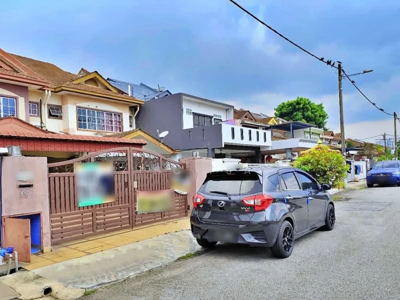 Exterior type: linked terrace house; features: two-storey building, brown painted facade, red tiled roof, white window frames, front garden with shrubs, paved driveway, fenced front yard, street view with parked cars, power lines visible, mature trees in vicinity; style: modern.