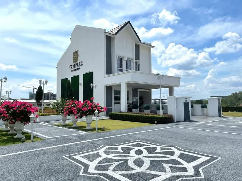 Exterior type: detached bungalow; features: white painted facade, pitched tile roof, manicured lawn, flower beds with pink bougainvillea, decorative stone-paved walkway, outdoor lighting fixtures, landscaped garden, parking area with marked spaces, signage on building, columns at entrance; style: modern.