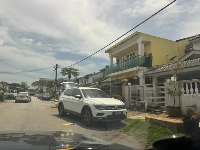 Exterior type: linked terrace house; features: yellow painted facade, balcony with glass railing, single-storey, manicured lawn, paved driveway, front garden with potted plants, surrounded by residential street, multiple vehicles parked on street; style: modern.