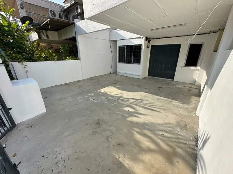 Exterior features: concrete flooring, white painted walls, single-storey structure, green door, windows with grilles, surrounding greenery, open space, no visible roof covering; style: modern.
