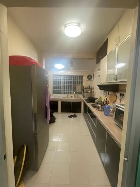 Kitchen features: grey cabinetry, light-colored countertops, stainless-steel fridge, built-in microwave, freestanding oven, sink with faucet, tile flooring, window with grid pattern, ceiling light fixture, open shelving, kitchen utensils and appliances visible, laundry basket, clothes hanging on a rack; style: modern.