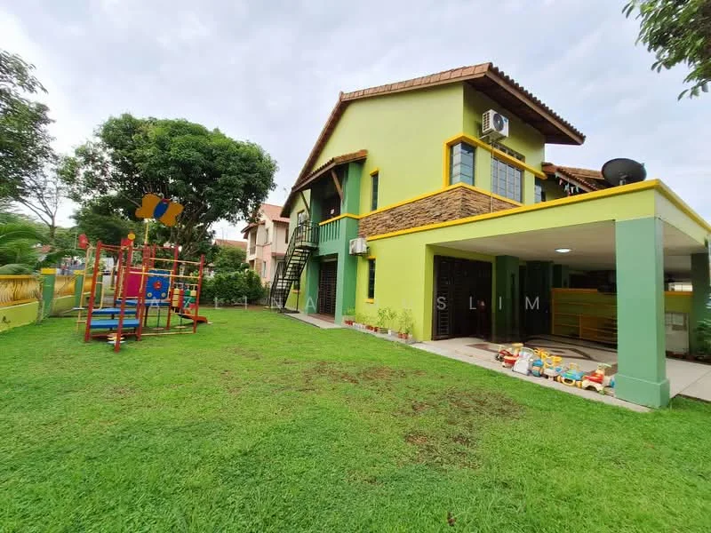 Exterior type: detached bungalow; features: green painted facade, brown tiled roof, two-storey structure, balcony with railing, garden area with manicured lawn, playground equipment, outdoor seating area, air conditioning unit on wall, staircase leading to upper level, surrounding greenery; style: modern.