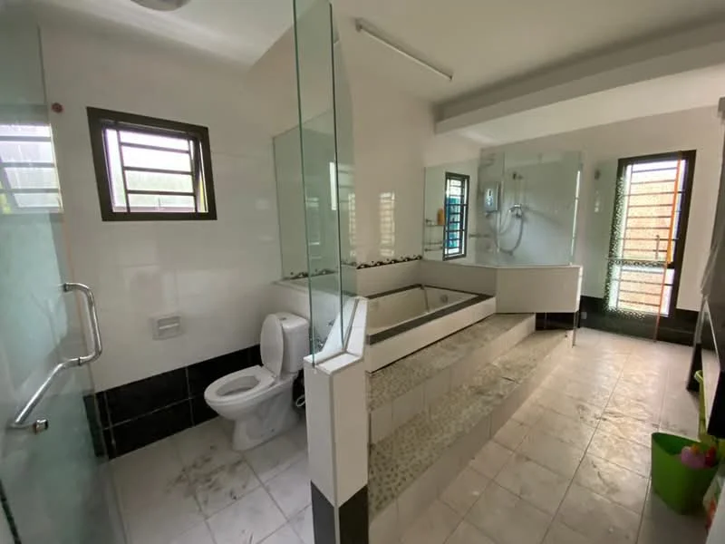 Bathroom features: white tiled walls, black tiled accents, glass shower enclosure, freestanding bathtub, one-piece toilet, single-sink vanity with cabinet, large mirror, recessed lighting, window for natural light, tile flooring, shower with handheld showerhead, built-in shelving, faucet with chrome finish; style: modern.