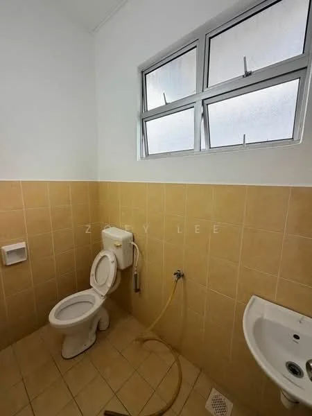 Bathroom features: white toilet, white sink, yellow tiled walls, beige tiled flooring, window with metal frame, exposed plumbing, toilet paper holder, handheld shower hose.