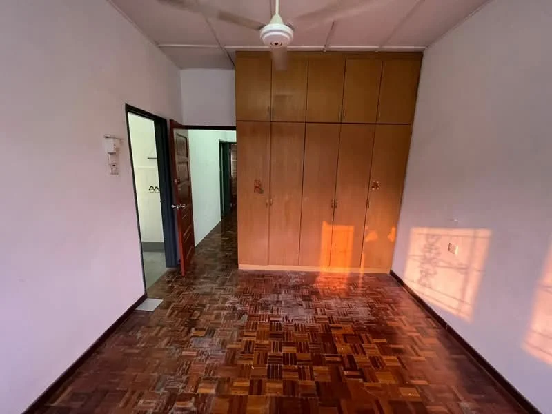 Room features: wooden flooring, built-in wardrobe with wooden doors, ceiling fan, white painted walls, door leading to hallway, natural light from window, sunlight casting shadows on floor; style: traditional.