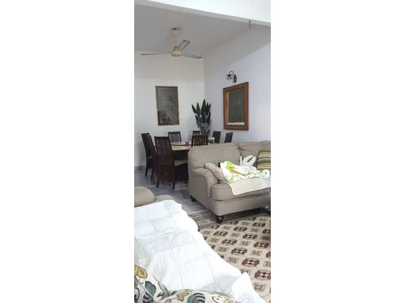 Living features: 3-seater fabric sofa in beige, 2-seater fabric sofa in beige, ceiling fan, area rug with geometric pattern, wooden dining table for 6, wooden dining chairs, framed artwork on walls, potted plant, white painted walls, tile flooring; style: modern.