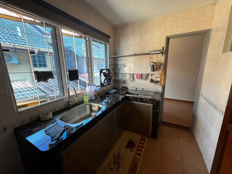 Kitchen features: single-bowl stainless-steel sink, chrome pull-down faucet, black granite countertop, wall-mounted shelving, cream tiled walls, brown tiled flooring, window with grid pattern, kitchen mat with coffee design, cabinets below countertop, dish rack, hanging utensils.