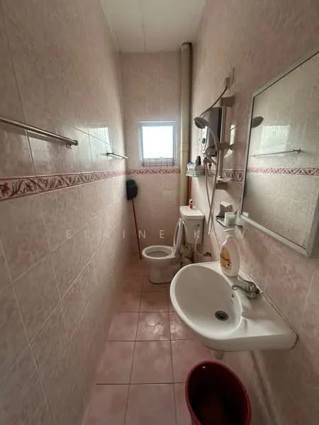Bathroom features: pink tiled walls, pink tiled flooring, white sink, chrome faucet, toilet, mirror, wall-mounted soap dispenser, window, towel rack, shower head, pipe, shelf.
