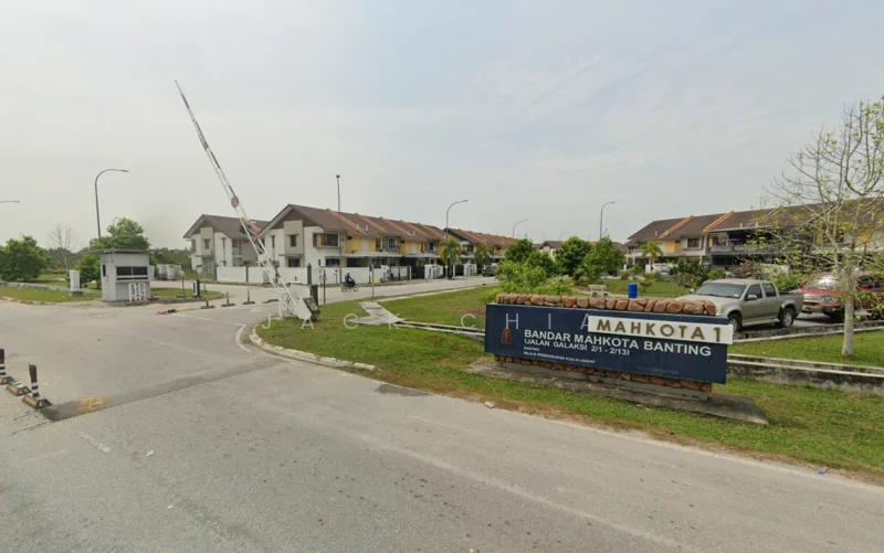 Exterior type: linked terrace house; features: gated entrance, guard house at entrance, paved road, landscaped greenery, street lighting, residential units with pitched roofs, signage for Mahkota 1, surrounding trees, open parking area; style: modern.
