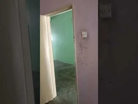 Room features: green painted walls, concrete flooring, doorway, light switch.