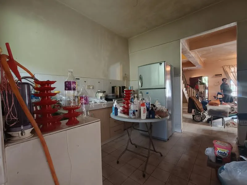Kitchen features: stainless-steel fridge, wood cabinetry, countertop with clutter, table with plastic cups, tile flooring, wall-mounted shelves, sink, kitchen appliances, light fixture, open layout to living area.