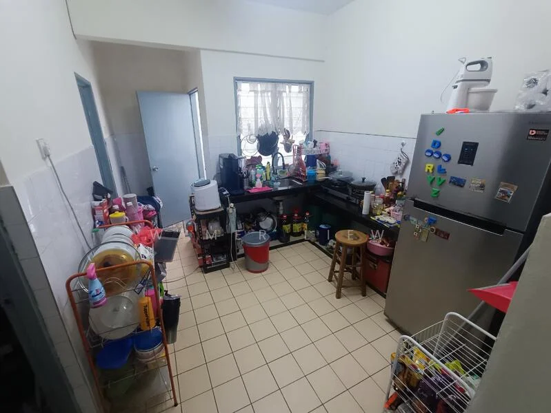 Kitchen features: stainless-steel fridge, black countertop, white tiled backsplash, white cabinets, sink, kitchen utensils, plastic storage containers, wooden stool, floor tiles, window with sheer curtains, various appliances, open shelving, dish rack, cleaning supplies.