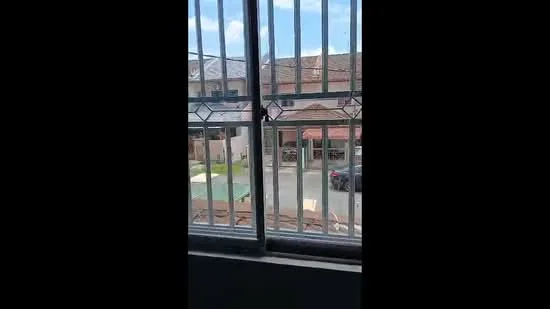Room features: window with metal grille, view of street, visible parked car, residential neighborhood, blue sky, roof of adjacent houses, green lawn, paved walkway; view: street.
