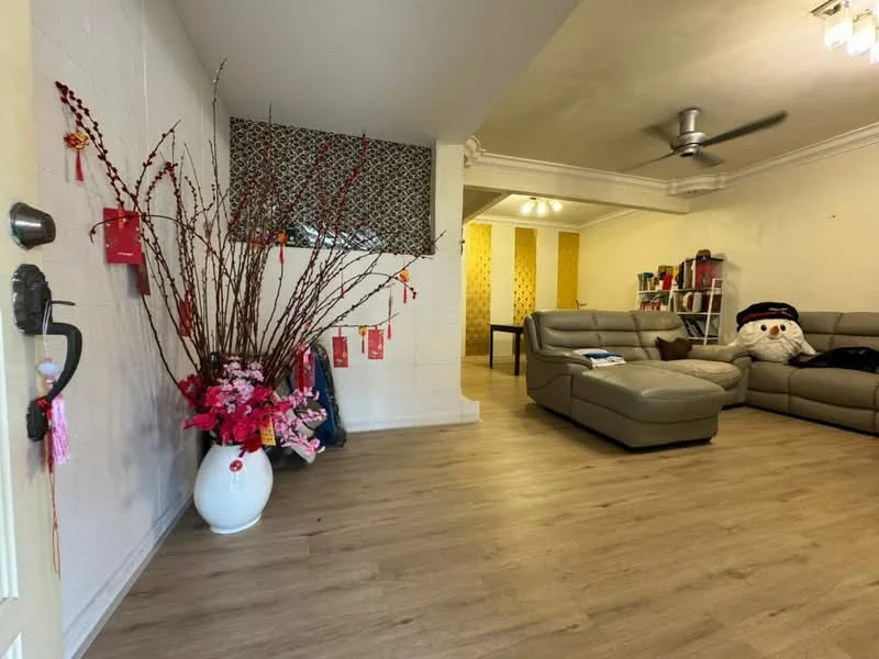 Living features: light wood laminate flooring, white painted walls, ceiling fan, 3-seater leather sofa in grey, decorative wall with patterned wallpaper, large decorative vase with flowers, wall-mounted bookshelf, decorative snowman plush, dining table visible in background, ambient lighting fixtures; style: modern.