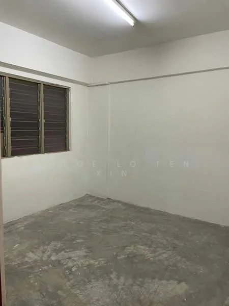 Room features: white painted walls, concrete flooring, two windows with metal grilles, fluorescent ceiling light.