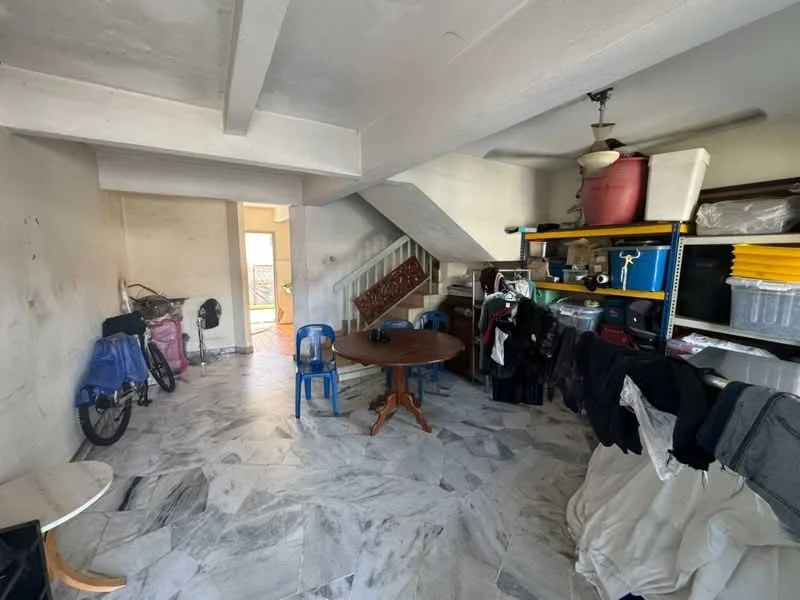 Room features: marble tile flooring, white painted walls, exposed beams on ceiling, ceiling fan, wooden staircase, round dining table, blue plastic chairs, bicycles, shelves with storage boxes, clothing on racks.