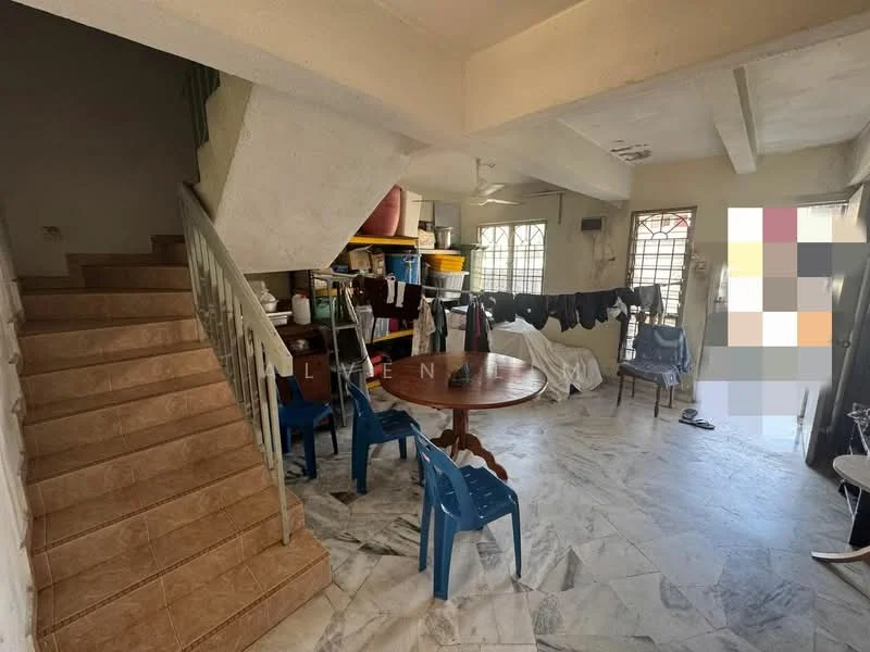 Room features: staircase with tiled steps, marble flooring, white painted walls, ceiling with exposed beams, round dining table, blue plastic chairs, clothes drying rack, open doorway leading outside, windows with metal grills, storage area with plastic bins, laundry area with clothes hanging.