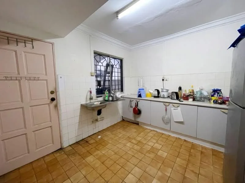 Kitchen features: white tiled walls, brown tiled flooring, single-bowl stainless-steel sink, chrome pull-down faucet, grey cabinetry with flat-panel doors, built-in countertop with space for appliances, refrigerator, microwave, kettle, toaster, various kitchen utensils and containers, window with metal grille, door with multiple panels.