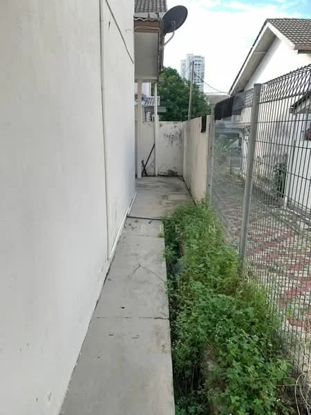 Exterior features: concrete pathway, fenced area, overgrown grass, adjacent building visible, satellite dish mounted, plain white walls.