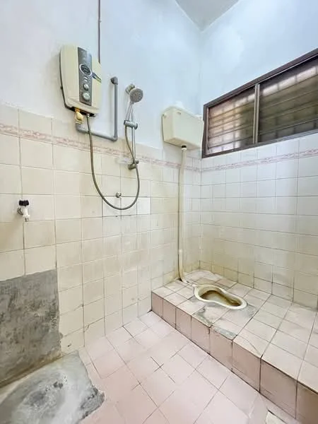Bathroom features: white tiled walls, pink tiled flooring, shower with handheld showerhead, water heater, toilet bowl, window for natural light, drainage area, wall-mounted faucet.