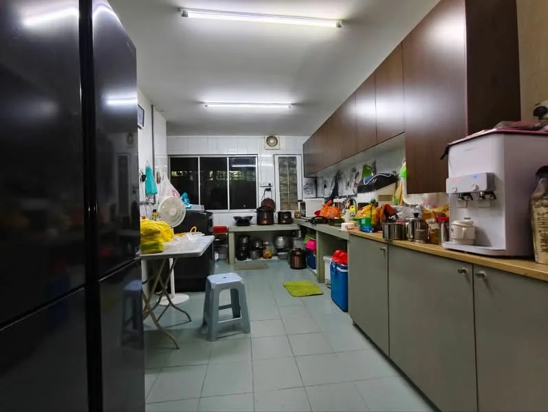 Kitchen features: black refrigerator, white table, plastic stool, wooden cabinetry, grey countertop, sink, kitchen appliances, various cooking utensils, tile flooring, overhead fluorescent lighting, window with natural light, wall-mounted shelves; style: modern.