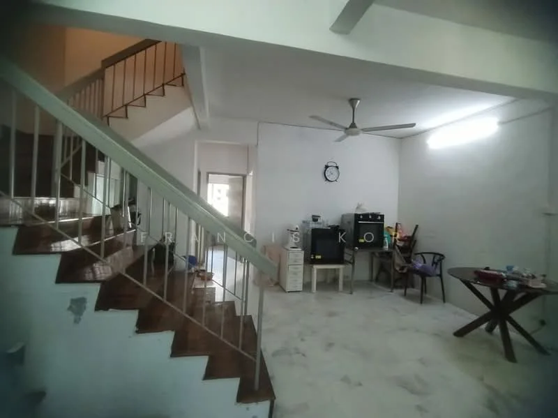Living features: white painted walls, tile flooring, ceiling fan, staircase with metal railing, dining table, wooden chair, kitchenette area with cabinets, wall-mounted clock.