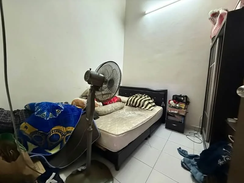 Bedroom features: single bed with mattress, black upholstered bed frame, striped bed linens, decorative cushions, wall-mounted light fixture, white painted walls, tiled flooring, standing fan, wardrobe with sliding doors, nightstand, various personal items on nightstand.