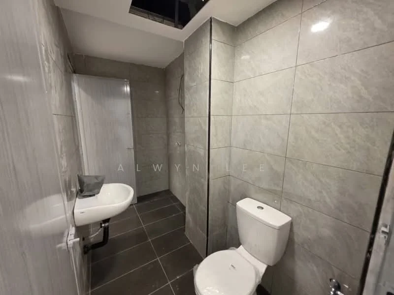 Bathroom features: grey tile cladding on walls, grey floor tiles, single-sink vanity with white basin, one-piece toilet, shower area with glass enclosure, wall-mounted shower head, mirror above sink, exposed plumbing, ceiling light fixture; style: modern.