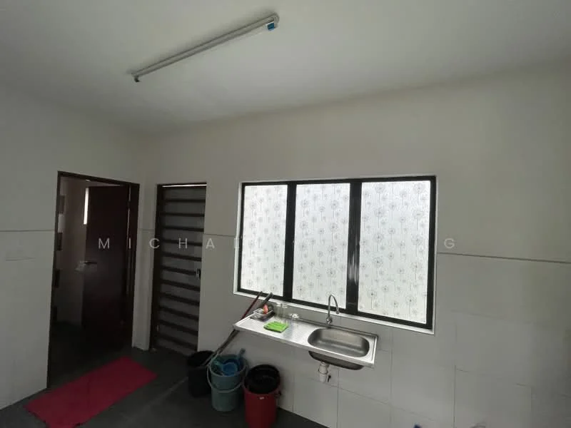 Kitchen features: single-bowl stainless-steel sink, chrome faucet, white tiled walls, grey tiled flooring, large window with patterned glass, door leading to hallway, multiple plastic buckets, pink mat on floor.