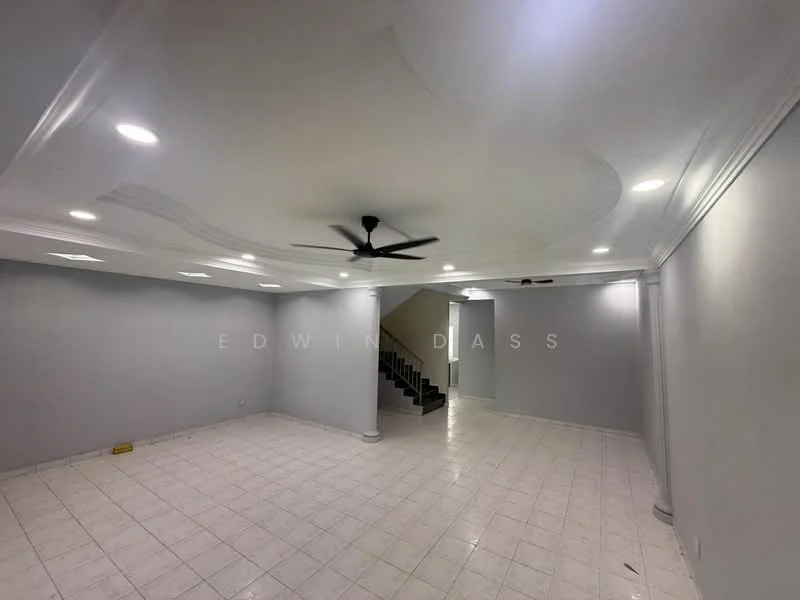 Room features: white painted walls, polished tile flooring, tray ceiling, recessed downlights, 5-blade ceiling fan, staircase visible in background, corner with no visible furniture, no visible windows or doors; style: modern.