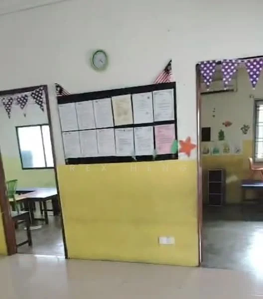 Room features: yellow painted walls, white ceiling, floor tiles, wall clock, decorative bunting, notice board with papers, window with curtains, table and chairs.