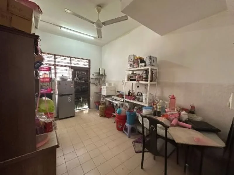 Kitchen features: white tiled walls, cream tiled flooring, ceiling fan, stainless-steel fridge, open shelving, wooden cabinet, table with chairs, various kitchen appliances, sink, multiple storage containers, window with metal grille.